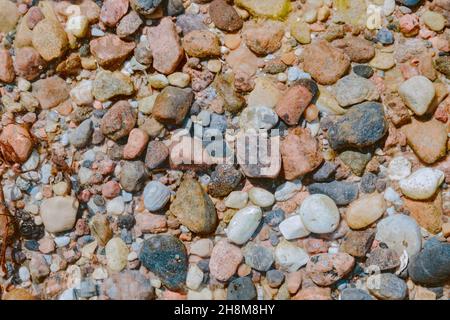 Bunte kleine Kieselsteine am Grund des Sees unter klarem Wasser Stockfoto