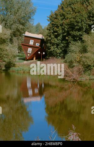 Malerischer Blick auf die Fee. Ein auf den Kopf gedrehtes Haus, ein umgestürzter Baum und ihre Spiegelungen in der Wasseroberfläche des Flusses. Stockfoto