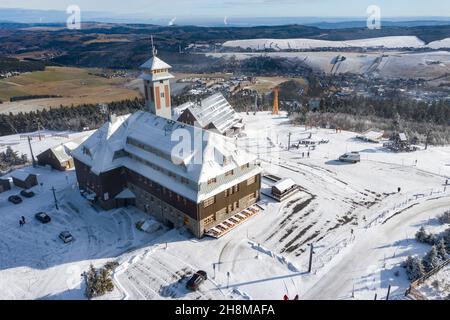 Oberwiesenthal, Deutschland. 23rd. November 2021. Eine dünne Schneeschicht liegt auf dem Gipfel des Fichtelbergs. Neben dem Fichtelberghaus ist die Seilbahn-Station zu sehen. (Luftaufnahme mit Drohne) Quelle: Jan Woitas/dpa-Zentralbild/dpa/Alamy Live News Stockfoto