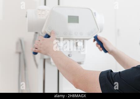 Röntgenabteilung im modernen Krankenhaus. Röntgenraum mit Scangerät und leerem Bett. Techniker, der ein Röntgengerät anpasst. Scannen von Brust, Herz Stockfoto