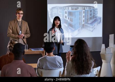 Geschäftsleute präsentieren auf dem großen Monitor ein neues Gebäude für die Teilnehmer einer Besprechung Stockfoto