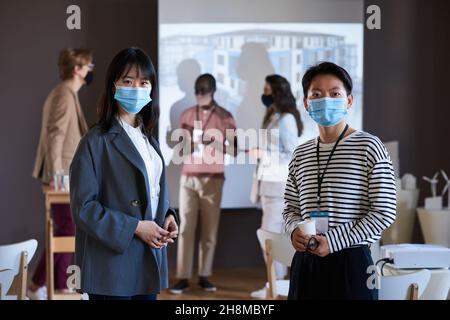 Porträt asiatischer Geschäftsfrauen in Schutzmasken, die beim Besuch eines Geschäftsseminars auf die Kamera blicken Stockfoto