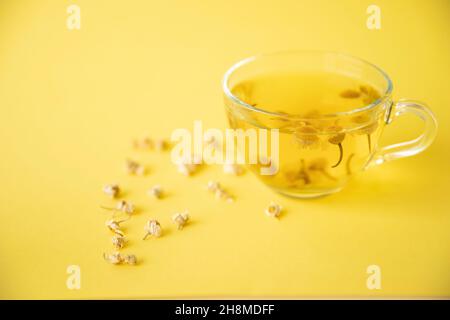 Kamillentee, der auf gelbem Hintergrund gebraut und in einer Glasschale serviert wird Stockfoto