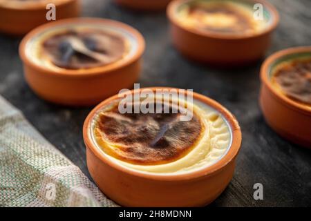 Reispudding Dessert in einem Tontopf im Ofen gekocht. Bereit zum Servieren auf schwarzem Präsentationboard Stockfoto