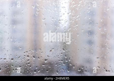 Abstrakter grauer Hintergrund von Regentropfen auf Glas. Das Konzept des Herbstes und des kalten stürmischen Wetters. Die Textur des Makros fällt auf den unscharfen Backgroun Stockfoto