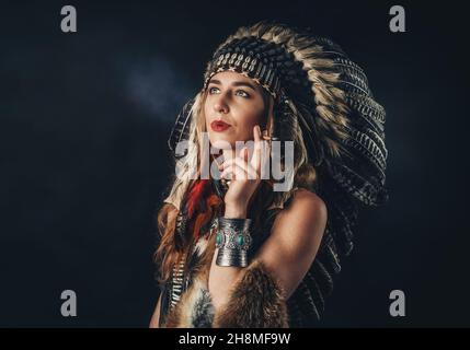 Schöne schamanische Mädchen im Studio auf schwarzem Hintergrund mit Zigarette in der Hand. Stockfoto