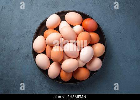 Hühnereier auf einem Teller auf dunklem Grund. Draufsicht, horizontal. Stockfoto