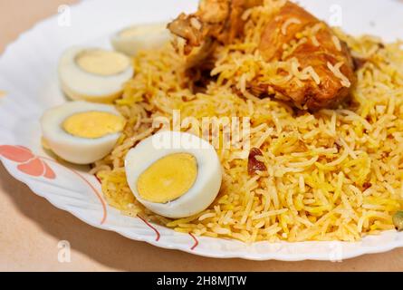 Würzige indische Biryani mit Hühnerkeule und in Scheiben geschnittenen Eiern in Nahaufnahme Stockfoto