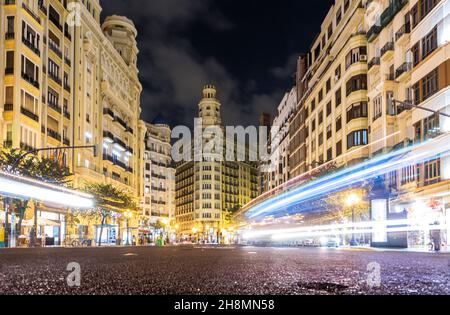 Langaufnahme der Lichtspuren von Fahrzeugen auf dem Hauptplatz von Valencia vom Asphalt aus, der seine Architektur zeigt Stockfoto