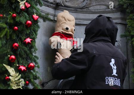 Brüssel, Belgien. 1st Dez 2021. Eine offizielle Kommode legt ein Kostüm auf den Manneken-Pis, um an den Welt-Aids-Tag in Brüssel, Belgien, am 1. Dezember 2021 zu erinnern. Die Aktion zielt darauf ab, die Öffentlichkeit für AIDS zu sensibilisieren. Quelle: Zheng Huansong/Xinhua/Alamy Live News Stockfoto