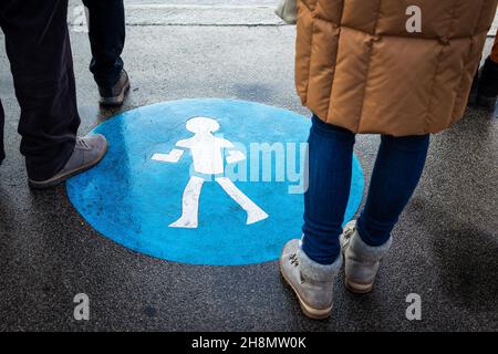 Leute warten auf Fußgängerüberwegen in der Stadtstraße. Straßenschild auf asphaltierter Straße. Menschliche Beine überqueren die Straße Stockfoto
