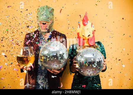 Verrücktes Paar mit Spaß halten Disco Kugeln und Champagner Glas auf der Party - konzentrieren Sie sich auf Hühnermaske Stockfoto