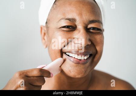 Ältere afrikanische Frau mit Spaß tun Hautpflege Behandlung - Fokus auf Augen Stockfoto