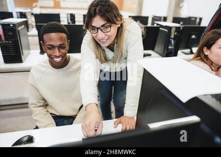 Lehrer, der mit Schülern im Computerraum arbeitet - Fokus auf das Gesicht der Frau Stockfoto