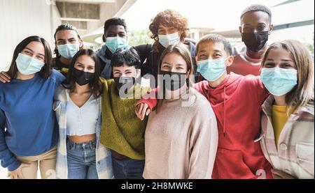 Porträt von multirassischen Freunden, die Spaß mit Sicherheitsmasken außerhalb des Universitätscampus haben Stockfoto