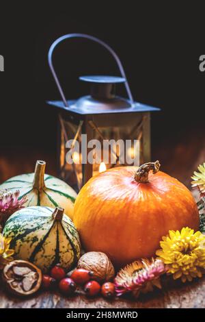 Herbsterntefest, Erntedankfest oder Halloween Hintergrund. Stillleben im Herbst. Kürbisse, Hagebutte, Walnuss, getrocknete Blume, Laterne Stockfoto