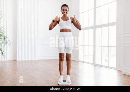 Glückliche Afroamerikanische Frau, Die Auf Einer Waage Steht. Schlankheitskonzept Stockfoto