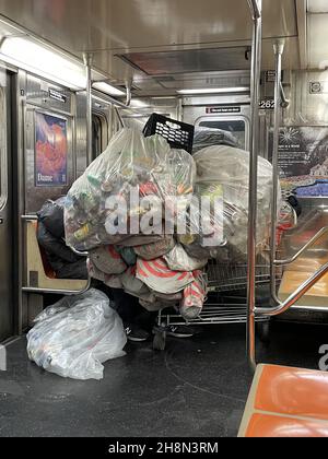 New York, NY, USA. 1st Dez 2021. Ein Obdachloser schläft im Zug 1 mit seiner Sammlung von Dosen zum Recycling, während die Temperatur weiter sinkt und die Bedrohung durch die Omicron Covid-Variante während der Weihnachtszeit in New York City am 1. Dezember 2021 droht. Kredit: Rainmaker Fotos/Media Punch/Alamy Live Nachrichten Stockfoto