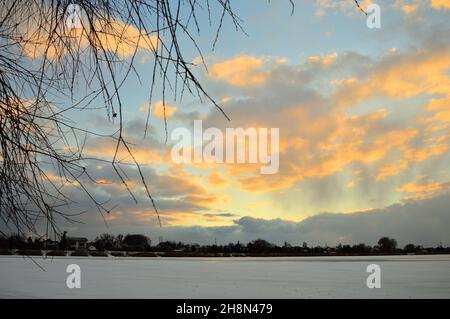 Ein gefrorener See, Schilf und Bäume am Horizont während eines Winteruntergangs. Winter. Stockfoto