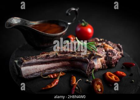 Ribeye-Steak mit Knochen, serviert mit Chili-Papper und Sauce Stockfoto