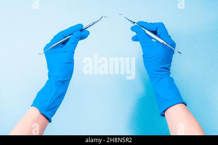 Hände in blauen Handschuhen, die Zahnwerkzeuge halten Stockfoto