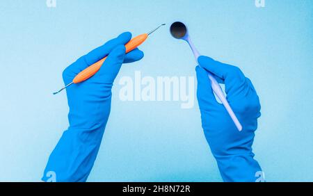 Hände in blauen Handschuhen, die Zahninstrumente halten Stockfoto