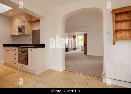 Cambridgeshire, England - November 4 2019: Hell dekorierter offener Küchenbereich mit Torbogen, der zum Wohnzimmer führt und keine Möbel hat Stockfoto
