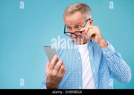 Überrascht reifer Mann mit Handy, Blick auf den Bildschirm Stockfoto