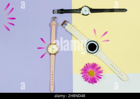 Stilvolle Damen Uhr auf einem farbigen Hintergrund mit Blumen und Platz für Text. Uhr in verschiedenen Farben Stockfoto