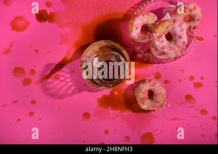 Das Konzept der Liebe für Donuts Espresso Kaffee und eine Menge Spritzer. Kreative bunte Donuts auf pastellrosa Hintergrund. Minimales Lebensmittelkonzept. Speicherplatz kopieren Stockfoto