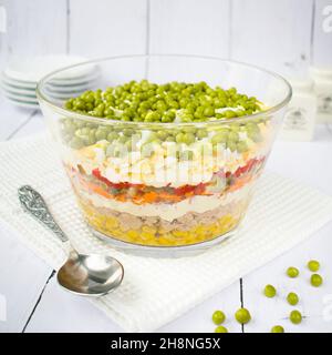 Hausgemachter geschichteter Salat mit Thunfisch, Karotten und Erbsen aus der Dose. Stockfoto