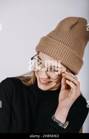 Unverfälscht offen emotionales Porträt einer jungen glücklichen Frau mit blonden langen Haaren auf grauem Hintergrund. Studio-Aufnahme von trendigen lässigen Hipster Mädchen in Stockfoto