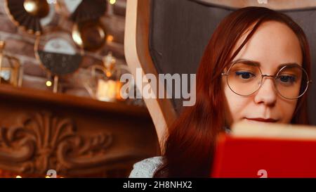 Junge Frau in Brille liest Buch. Interessierte Schüler in Brillen liest Buch und bereitet sich auf den Unterricht vor. Nahaufnahme Stockfoto