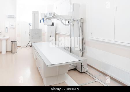 Röntgenabteilung im modernen Krankenhaus. Röntgenraum mit Scangerät und leerem Bett. Techniker, der ein Röntgengerät anpasst. Scannen von Brust, Herz Stockfoto