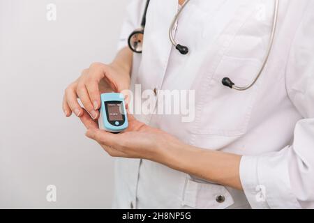 Pulsoximeter mit der Hand des Arztes auf Weiß isoliert. Das Konzept eines tragbaren digitalen Geräts zur Messung der Sauerstoffsättigung von Personen. Messung von Sauerstoff Stockfoto