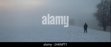 Einzelfigur eines Mannes, der in starkem Nebel am Flussufer entlang läuft, Ribble Valley, Lancashire, Großbritannien. Stockfoto