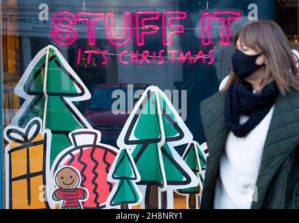 Edinburgh, Schottland, Großbritannien. 1st. Dezember 2021. Mitglieder des öffentlichen Spaziergangs mit Gesichtsmaske gehen an einem für Weihnachten geschmückten Schaufenster im Stadtzentrum von Edinburgh vorbei. Die schottische Regierung warnt davor, dass Menschen von zu Hause aus arbeiten sollten, um die Ausbreitung der omicron-Variante des Covid-19-Virus zu minimieren und das Risiko einer Unterbrechung der Weihnachtsfeierlichkeiten zu minimieren. Masterton/Alamy Live News. Stockfoto