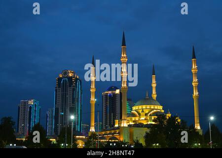 Grosny, Tschetschenien, Russland - 13. September 2021: Akhmad Kadyrow Moschee im Herzen Tschetscheniens und Wolkenkratzer der Innenstadt bei Nacht Stockfoto