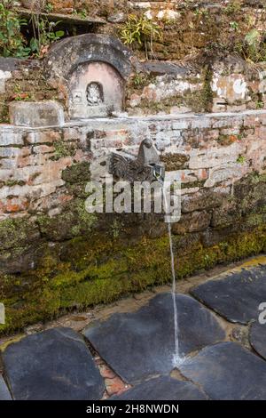 Geschnitzte Steindrachen sprudeln Quellwasser am Teendhara-Brunnen im Newari-Dorf Bandipur, Nepal. Stockfoto