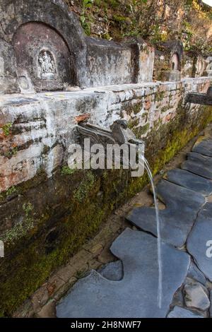 Geschnitzte Steindrachen sprudeln Quellwasser am Teendhara-Brunnen im Newari-Dorf Bandipur, Nepal. Stockfoto