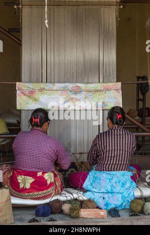 Zwei Frauen weben einen Teppich auf einem Fußwebstuhl im mittelalterlichen Dorf Bungamati, Nepal. Stockfoto