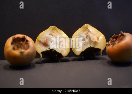 Essbare Mispellanobst (mespilus germanica, Familie rosaceae). Mispel-Früchte sind im Winter erhältlich und werden beim Bletten verzehrt. Querschnitt Mispel Stockfoto