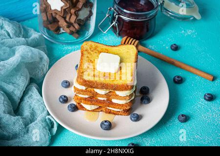 French Toast mit Banane, Heidelbeere, Honig und Erdbeermarmelade. Köstliches Frühstück oder Brunch mit Toast und Keksen Stockfoto