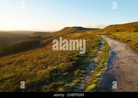 Ein frostbedeckter Fußweg führt entlang der Hänge des Burbage Valley zu einem entfernten Higger Tor. Stockfoto