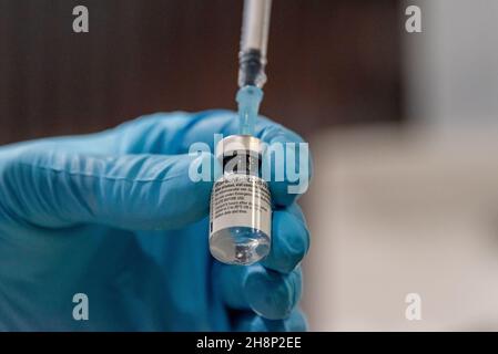 Hände mit Impfstoffampulle und Spritze beim Aufziehen des Impfstoffes gegen das Covid-19 Virus Stockfoto
