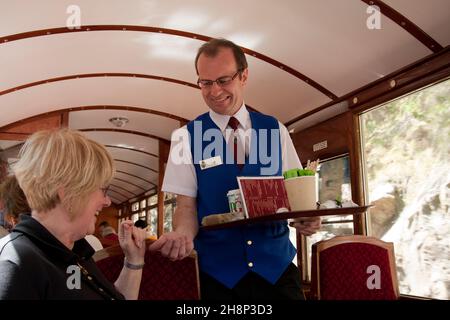 Steward für reife Frauen, die allein auf der Dampfeisenbahn Blaenau Ffestiniog, Gwynned, Wales, reisen Stockfoto