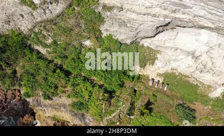 Gefährlicher Holzweg, der an einer vertikalen Klippe hängt. Extrem gefährlicher Fußweg auf einer Felswand zum Seganing Wasserfall. Rocky Cliff und Stockfoto