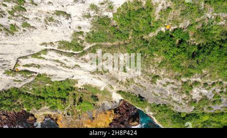 Extrem gefährlicher Fußweg auf einer Felswand zum Seganing Wasserfall. Felsenküste und Wanderweg am Berg in der Nähe des Strandes von Kelingking. Luftaufnahme Stockfoto