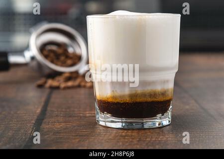 Cortado-Kaffee mit Kaffeebohnen daneben. Traditioneller Kaffee in Spanien. Stockfoto