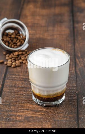 Cortado-Kaffee mit Kaffeebohnen daneben. Traditioneller Kaffee in Spanien. Stockfoto